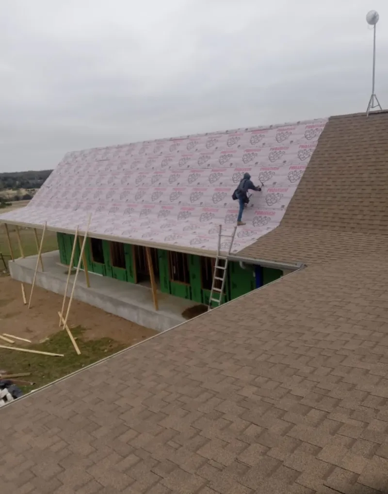 Worker preparing underlayment for a metal roof installation in Fitchburg